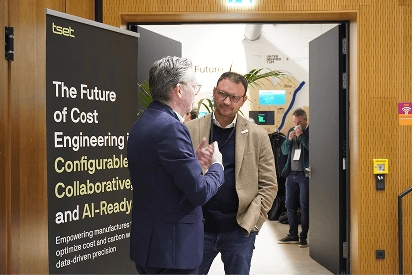 Two men converse near a Tset event banner in a hallway.