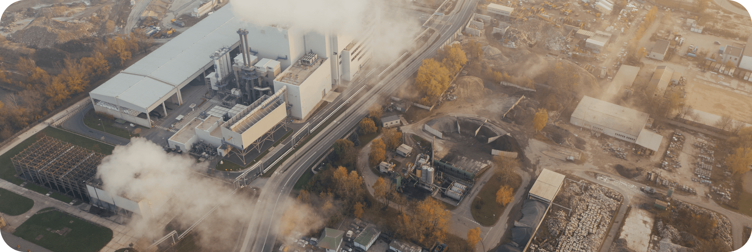 Aerial view of industrial manufacturing site with visible emissions