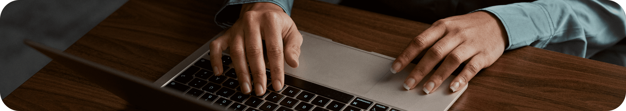 Close-up of hands typing on a laptop keyboard on a wooden desk, suggesting focused digital work. Close-up of hands typing on a laptop keyboard on a wooden desk, suggesting focused digital work.