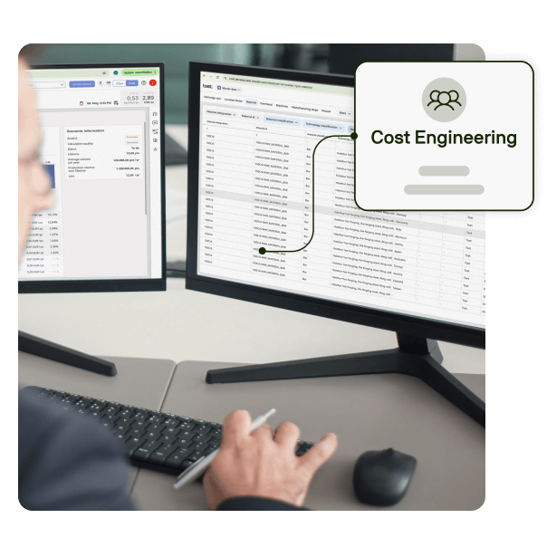 A person working at a desk with two computer monitors displaying cost engineering software.