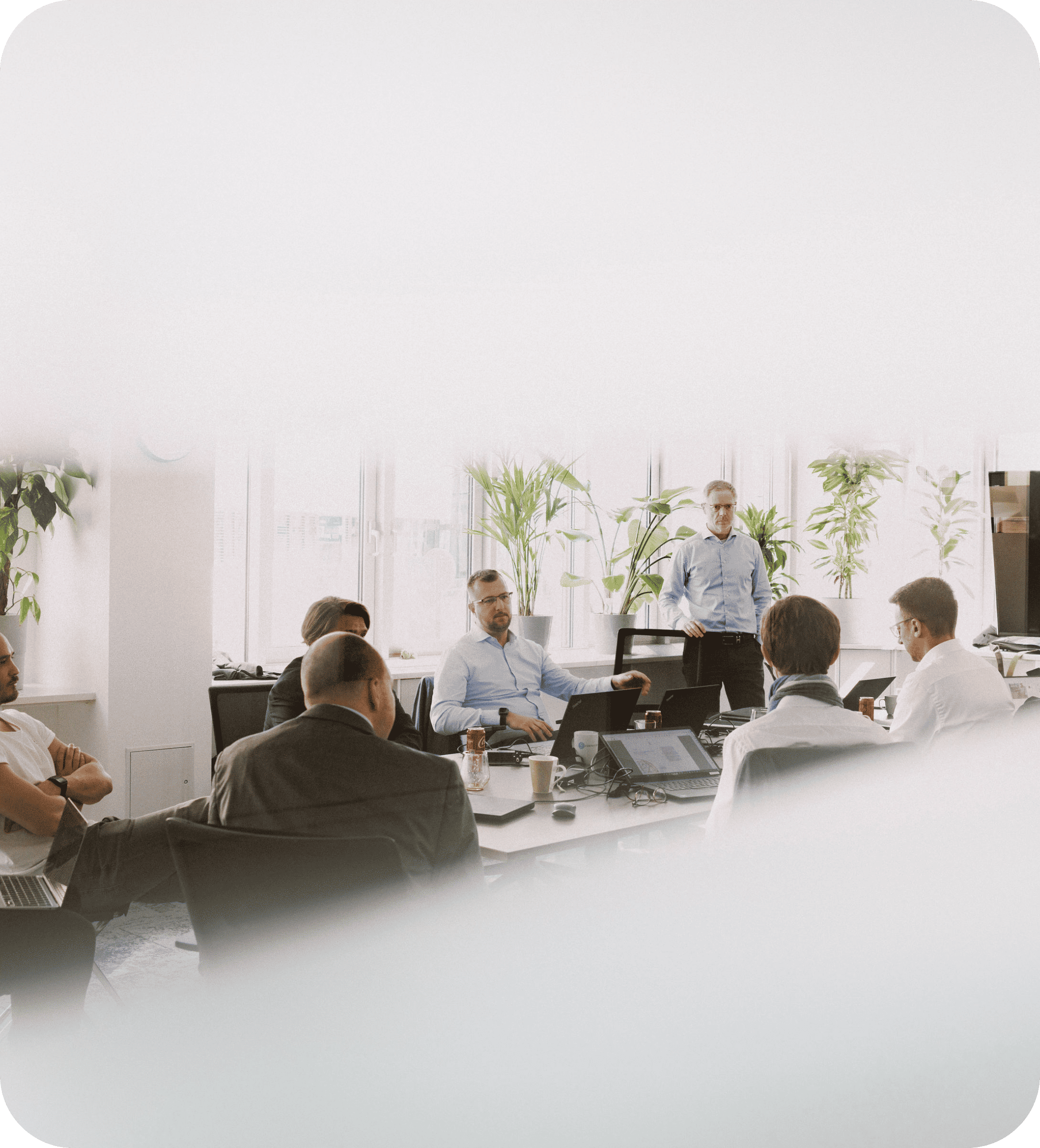 Ein Führungsteam in einem hellen Besprechungsraum, das an einem Konferenztisch die Strategie diskutiert.
