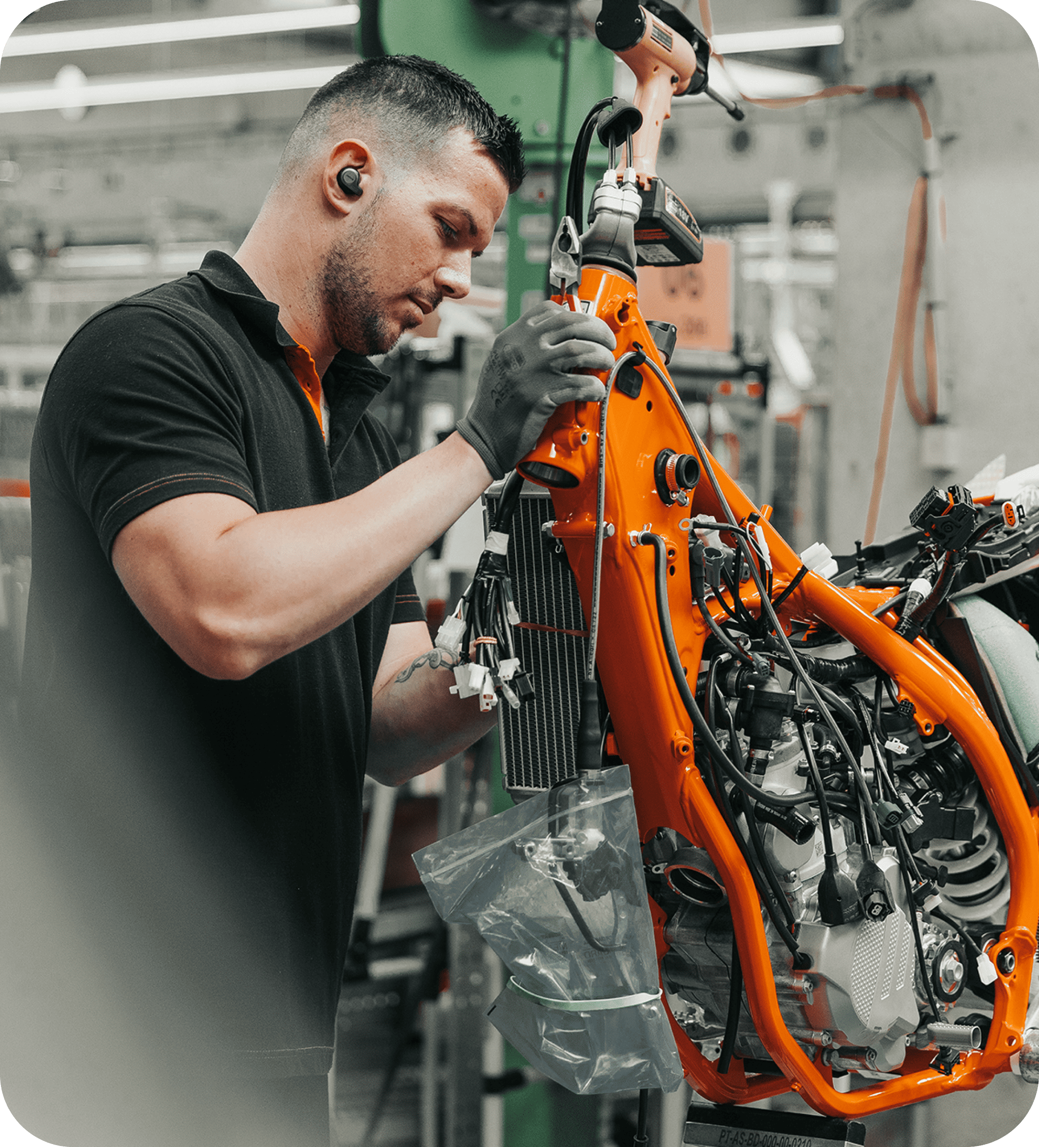Technician assembling a KTM motorcycle frame, highlighting craftsmanship and precision in high-performance motorbike production.