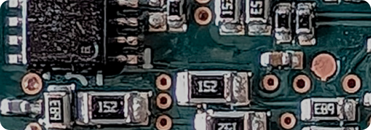 Close-up of a green circuit board with various black microchips, silver pins, and copper traces. Numbers